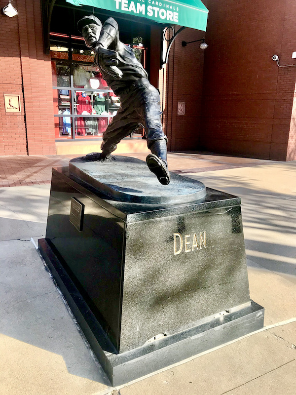 A bronze sculpture of a baseball play with a catchers mitt trying to catch a ball.