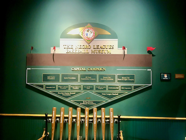 A green wall with plaques of donors names and baseball bats at the Negro Leagues Baseball Museum