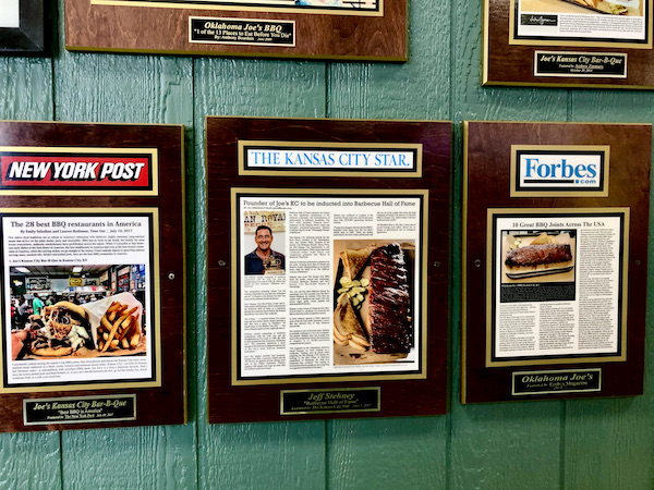A dark green paneled wall with several framed magazine articles hanging on it.