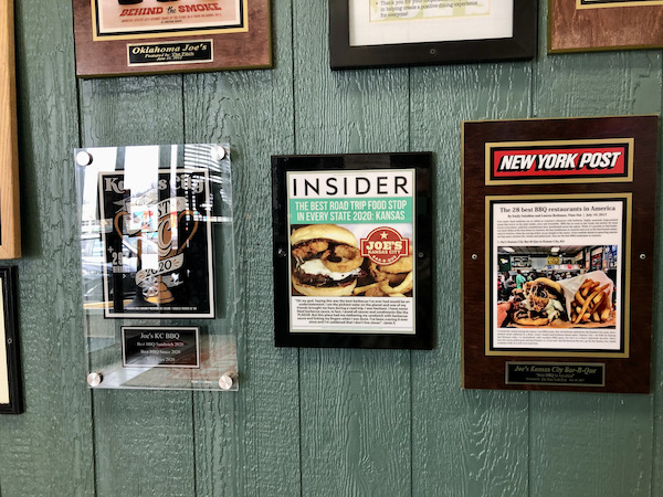 A dark green wall with framed magazine articles hanging on it.