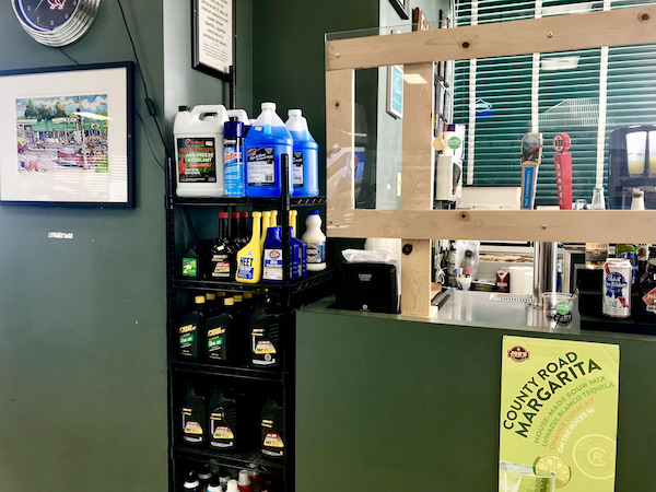 A cashier's window with a display of motor oil on a stack of shelves.