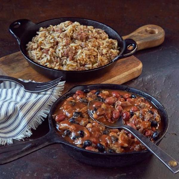 Cast iron skillets filled with dirty rice and baked beans.