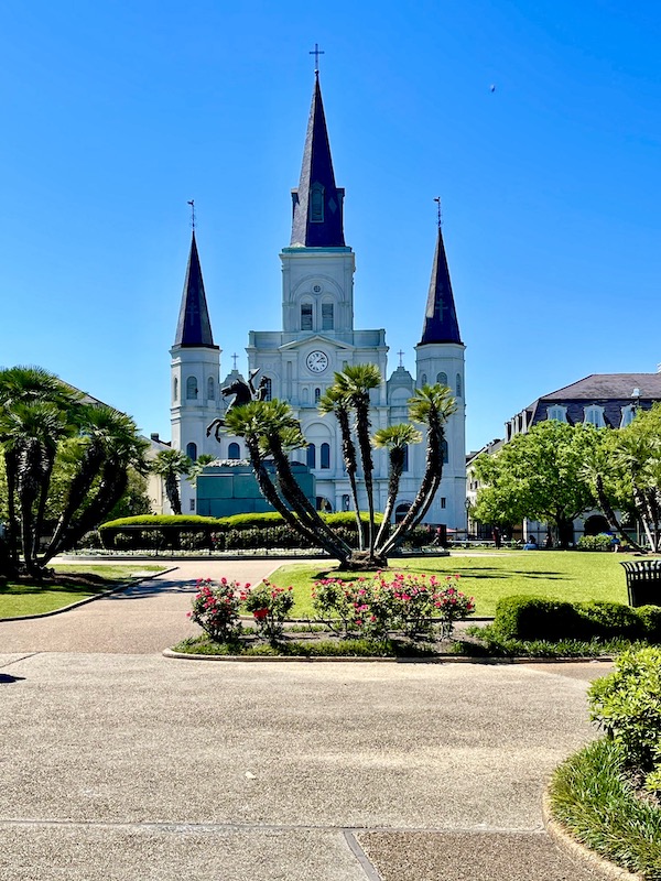 A white cathedral with black spires at the end of a park visited while Back in NOLA for a Month 