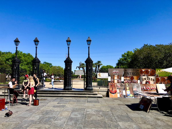 Musicians on the left and artwork on the right of the photo with trees and deep blue sky in the background.