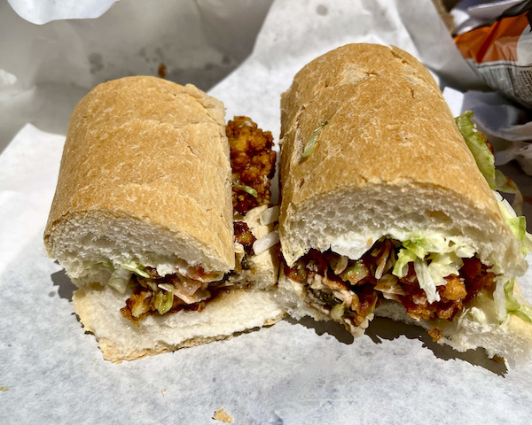 White deli paper topped with a hoagie roll filled with fried oysters eaten while Back in NOLA for a Month