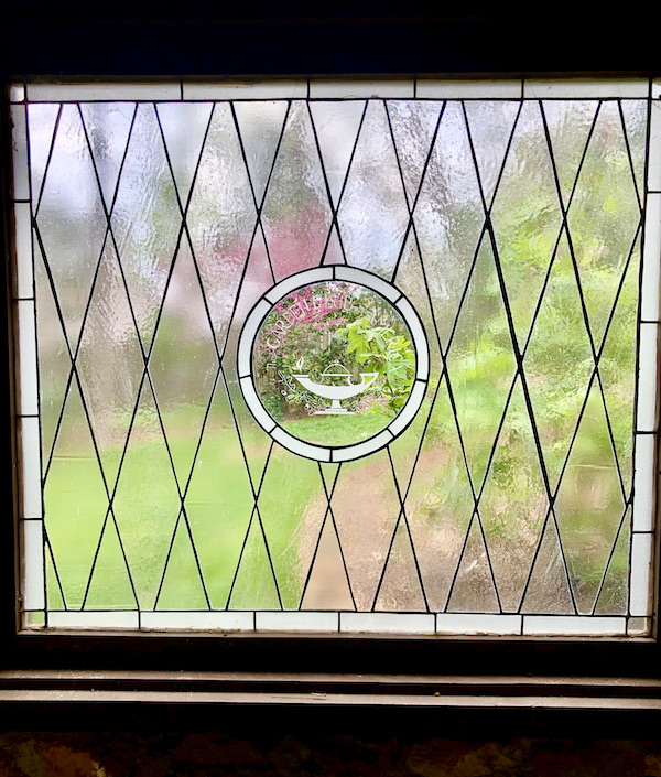 A leaded glass window with medallion in center honoring the Garden Club of America.