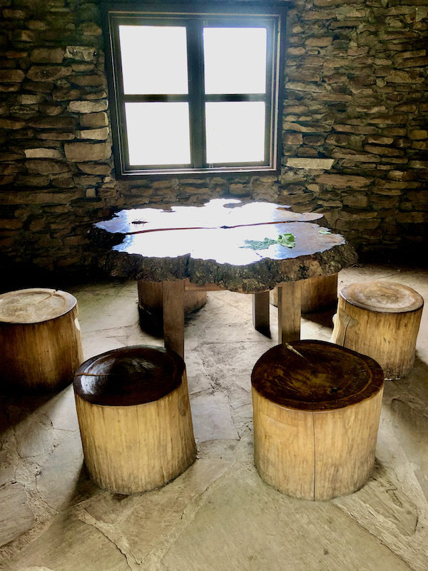 Inside a brick building with a table top that is a slice of a tree and stools from tree trunks at Cheekwood Estate Nashville TN