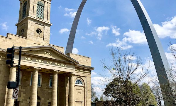 A church building with the Gateway Arch Saint Louis MO in the background.
