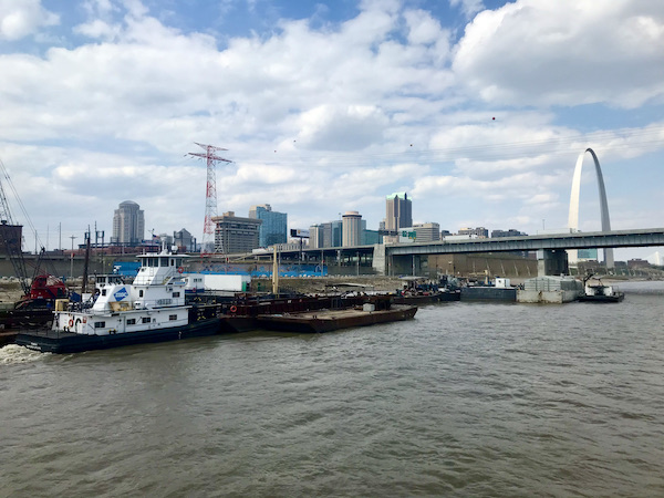 A harbor with tug boat, buildings and muddy water near the Gateway Arch Saint Louis MO