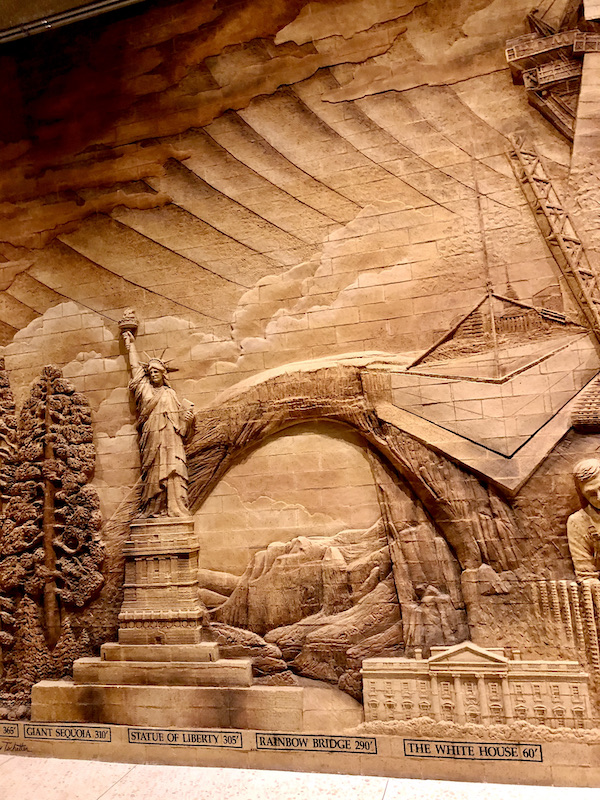 A brick carving depicting the statue of liberty, white house and rainbow arch in the Gateway Arch
