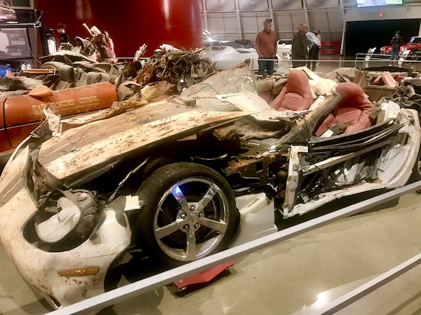 A brown and a white Corvette showing damage from falling into the sinkhole at the National Corvette Museum