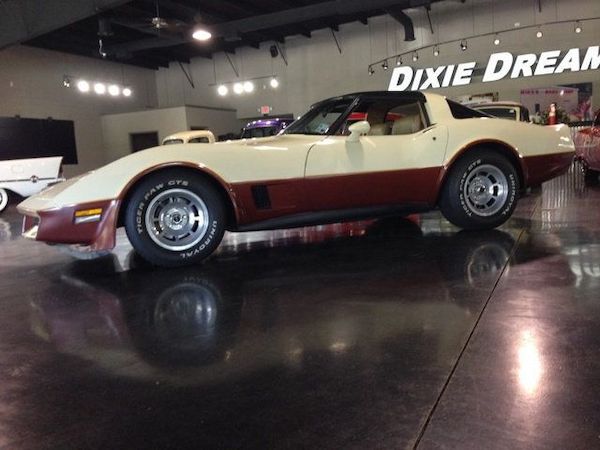 A cream and bronze corvette on a garage floor.