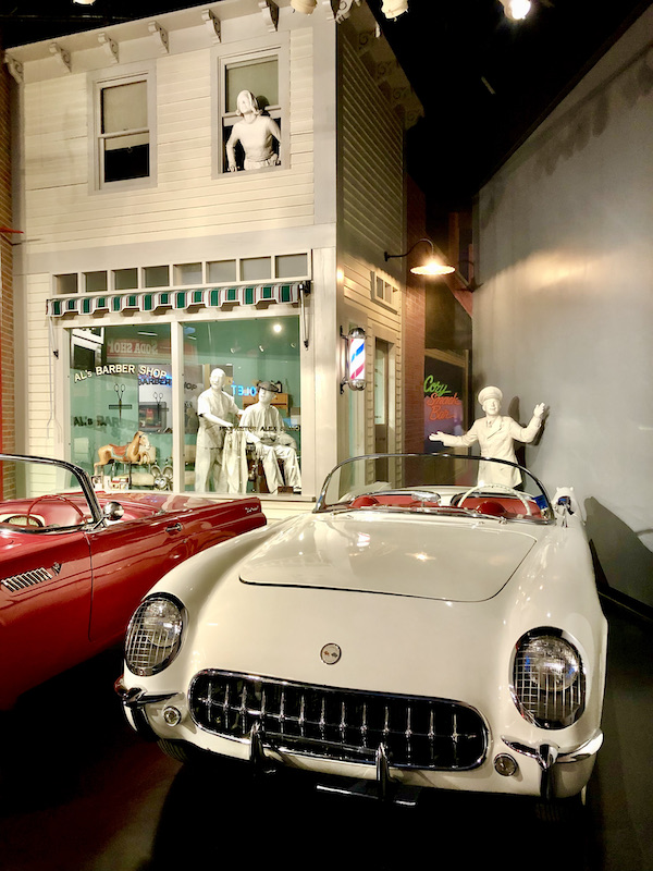 White figures representing people in 1953 showing the new Corvette at the National Corvette Museum