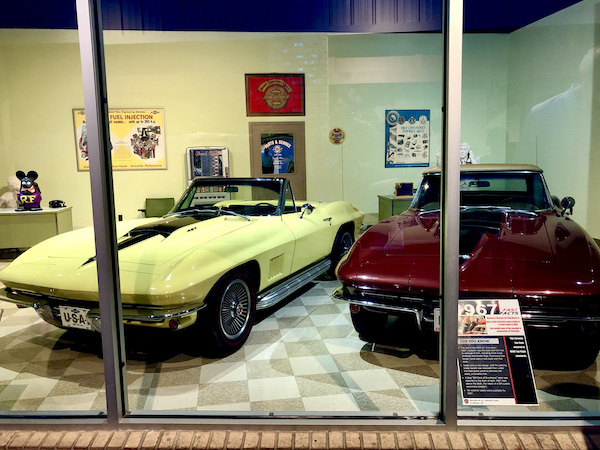 A yellow and a burgundy sports car on display at the National Corvette Museum