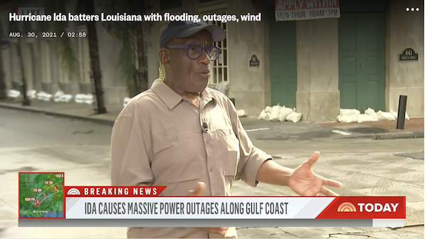 A man standing in a street in front of buildings lined with sand bags. Prayers for those hit by Ida