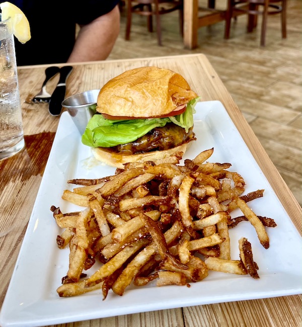 A white oblong plate topped with a burger in a bun and french fries at Café Hope Gretna Louisiana