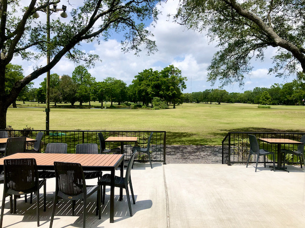 A patio with table and chairs abutting a golf course at Café Hope Gretna Louisiana
