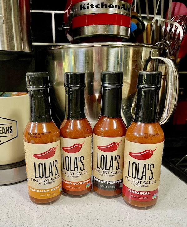 Four bottles of hot sauces on a kitchen counter from Fabulous Gifts for Campers