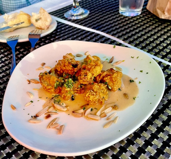 A white plate topped with fried oysters, toasted almonds and sauce at Maple Street Café New Orleans