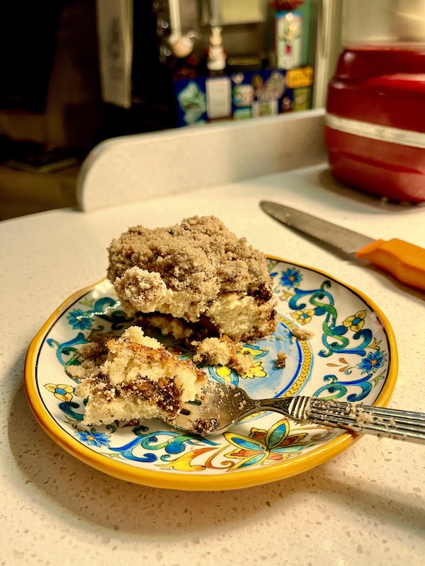 A yellow and blue plate topped with a piece of cake and a dessert fork.