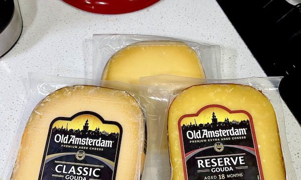 A trio of wrapped cheeses laying on white paper.