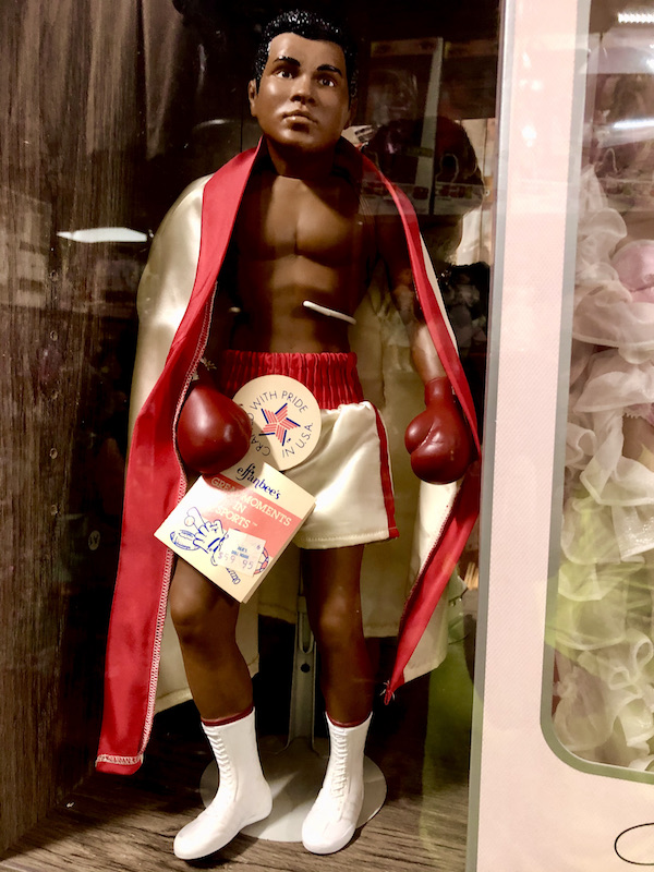 A doll in a box that is Mohamed Ali in boxing attire complete with red cape.