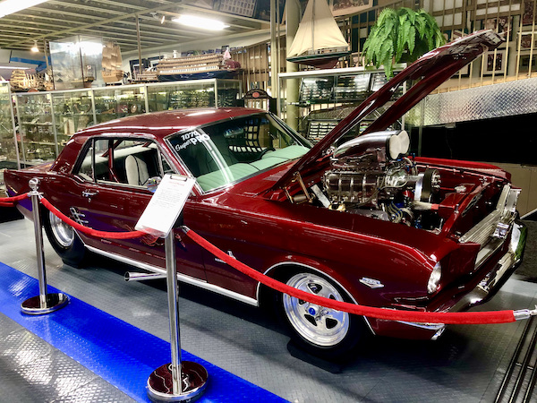 A burgundy Ford Mustang Dragster with hood up.