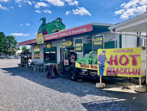 A large market with colorful signs offering fresh seafood and more.
