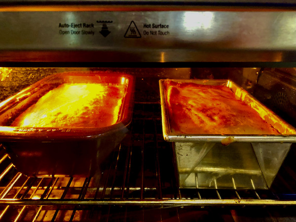 Two lemon cakes in loaf pans baking in the oven.
