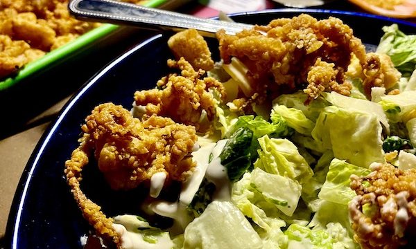 A large plate of salad topped with crispy calamari at Lucky Fish Restaurant Pompano Beach FL