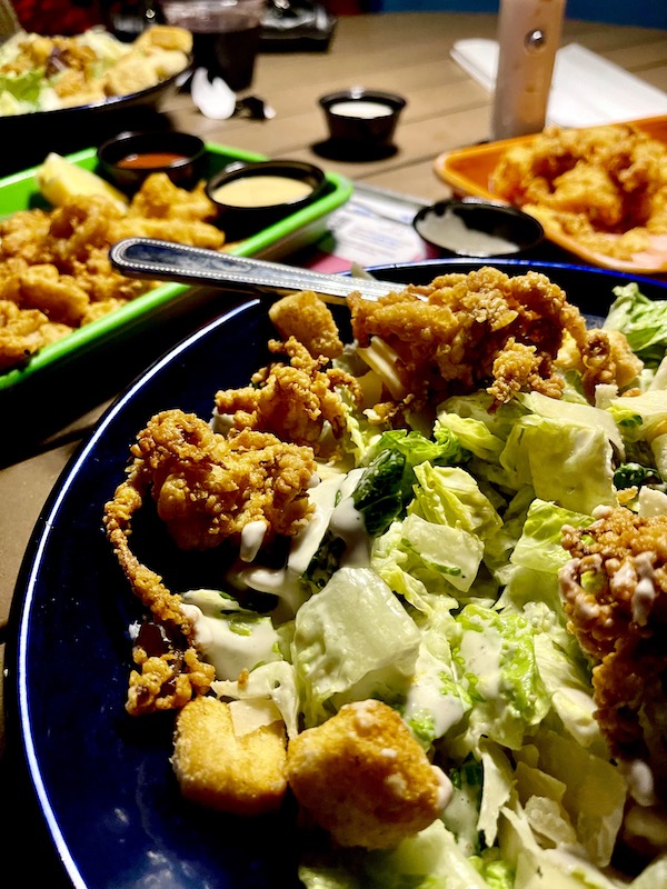 A large plate of salad topped with crispy calamari at Lucky Fish Restaurant Pompano Beach FL