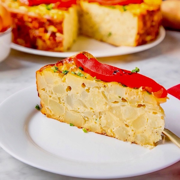 A wedge of a potato and egg cake topped with a strip of red pepper from Sobremesa - A Memoir of Food and Love.