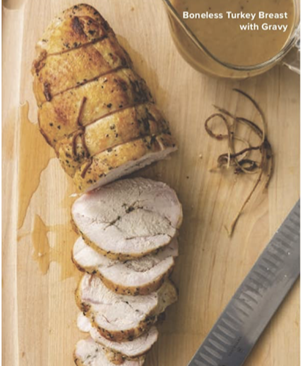 A cutting board topped with a partially sliced turkey breast and a measuring cup filled with gravy from The Complete Autumn and Winter Cookbook