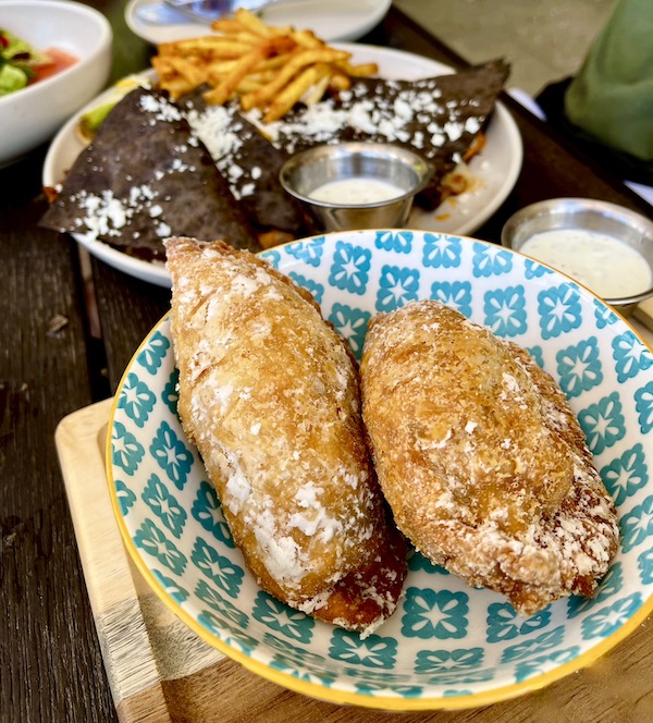 A blue and yellow plate topped with two hand held empanadas at Viva La Playa at Lake Worth Beach