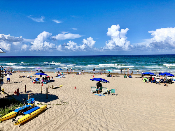 Umbrellas, sunbathers, beach and ocean across from Viva La Playa at Lake Worth Beach