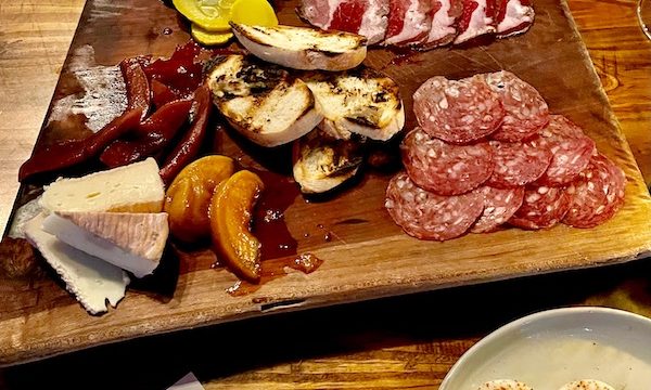 A wood board topped with assorted sliced meats, fruit, cheese, crostini and jam at Bacon Bros Public House Greenville SC