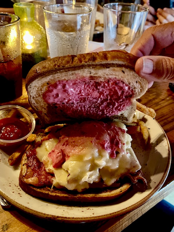 A Reuben sandwich with deep pink dressing on the top slice of bread at Bacon Bros Public House Greenville SC