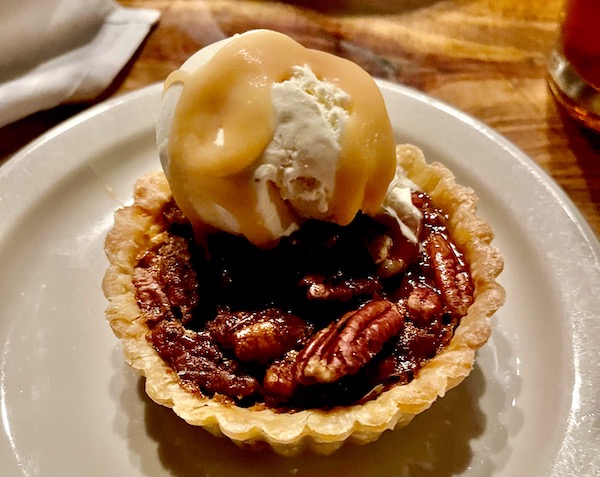A plate topped with an individual pecan pie and ice cream with caramel sauce at Bacon Bros Public House Greenville SC