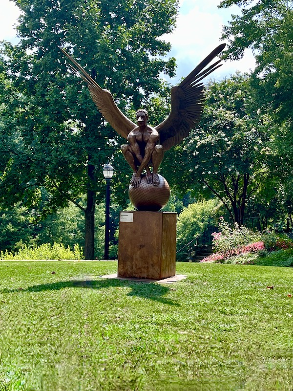 A bronze sculpture of a crouching man with eagle wings perched on a sphere in Beautiful Greenville South Carolina