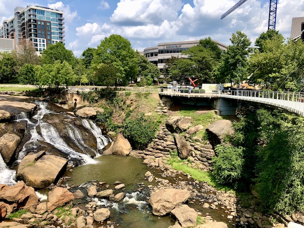 A bridge curves through a park with rocks and waterfalls below in Beautiful Greenville South Carolina