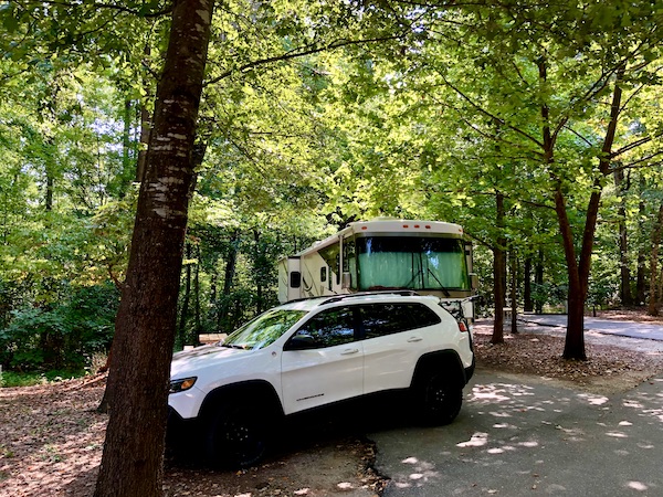 A white SUV parked in front of an RV in the woods near Beautiful Greenville South Carolina