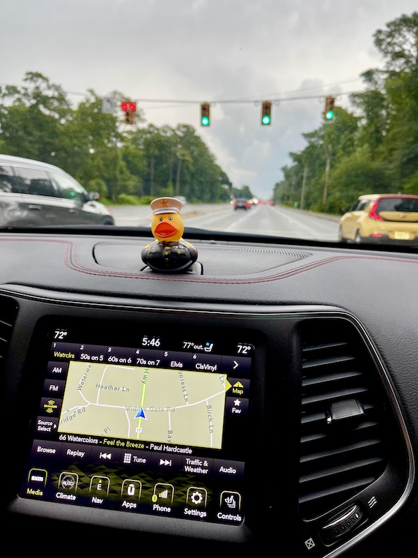 A rubber duck dressed as an Admiral sits atop a dash inside our Jeep.