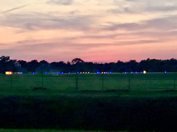 Sky of pink, purple and blue over a grassy air strip.
