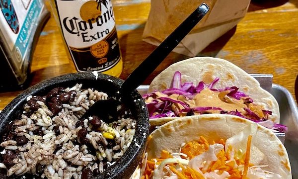A bottle of Corona beer, a pair of tacos and a black dish of black beans and rice at Taco Mundo North Myrtle Beach