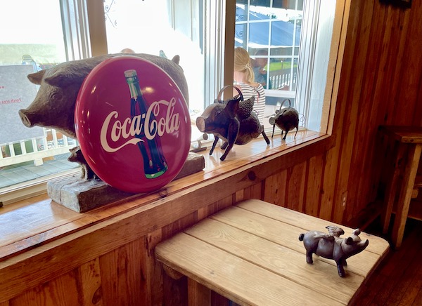 Several metal pigs and a coca cola sign at the bbq exchange.