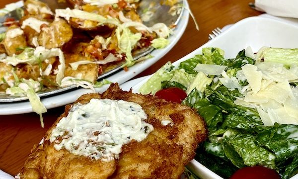 Several platters of food on a table including a breaded fish sandwich and a salad at Mudhen Brewing Wildwood NJ