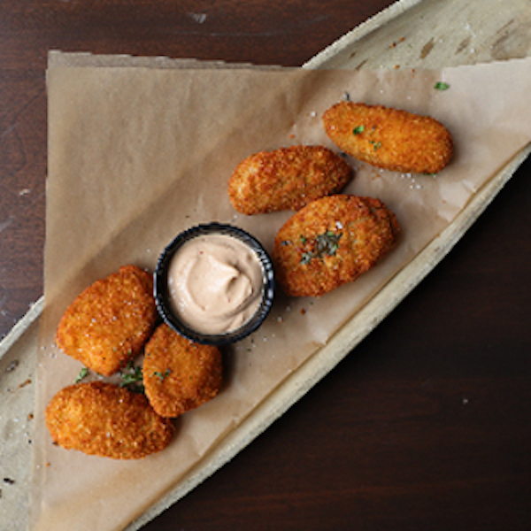 An oval platter topped with brown paper and battered and stuffed fried jalapenos plus a dipping sauce at Mudhen Brewing Wildwood NJ