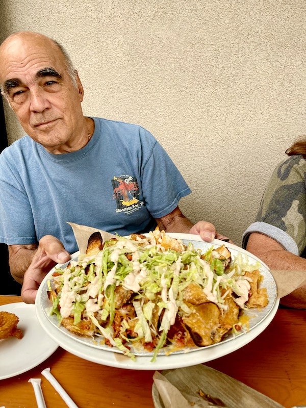 A man in a blue T-shirt offering a plate of nachos at Mudhen Brewing Wildwood NJ