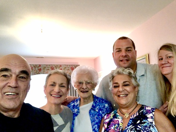 Two men and three women clustered together for a photo in the living room.