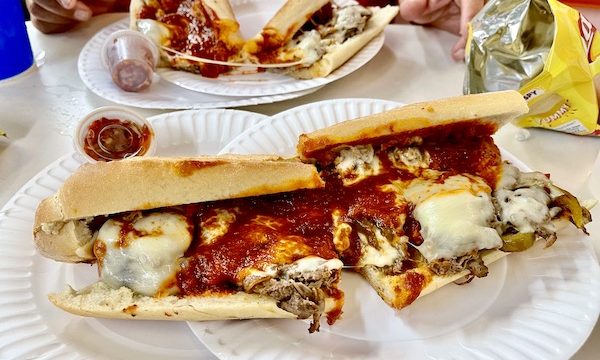 Two plates topped with cheesesteaks with tomato sauce on Our Pilgrimage to the Jersey Shore
